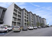 Multi-story condo building with grey exterior, balconies, parking lot, and blue sky at 5905 South Kings Hwy. # A518, Myrtle Beach, SC 29575
