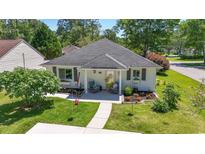 Charming single-story home featuring a well-manicured lawn, inviting front porch with rocking chairs, and lovely landscaping at 6630 W Sweetbriar Trail, Myrtle Beach, SC 29588