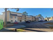 A beige condo building with wood balconies, surrounded by parking spaces and blue skies on a sunny day at 1025 W Plantation Dr. W # 2817, Little River, SC 29566