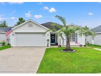 Charming single-story home with a well-manicured lawn, garage, and a welcoming front entrance at 127 Coachman Ln., Surfside Beach, SC 29575