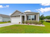 Charming single-story home featuring a manicured lawn, white garage door and tasteful landscaping at 171 Cassina Dr., Longs, SC 29568