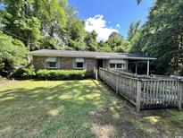 Brick home featuring a ramp for accessibility surrounded by mature trees and greenery at 41 Harmon St., Hemingway, SC 29554