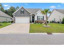 Charming single-story home featuring a well-manicured lawn, palm tree, and a two-car garage at 462 Pacific Commons Dr., Surfside Beach, SC 29575