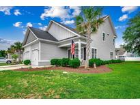 Charming two-story home featuring a landscaped yard, attached garage, and a welcoming front porch with an American flag at 620 Lorenzo Dr. # 620, North Myrtle Beach, SC 29582