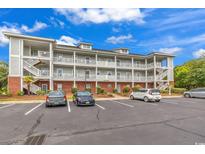 Multi-story condominium with brick and siding exterior, white railings, parking and blue sky at 701 Salleyport Dr. # 1117, Myrtle Beach, SC 29579