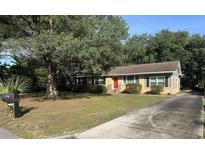Charming single-story home featuring a red front door and a well-maintained yard and mature tree at 7708 Woodland Dr., Myrtle Beach, SC 29572