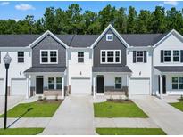 Charming townhomes showcasing a blend of gray and white exteriors, complemented by lush greenery and private driveways at 776 Nw Palm Frond Way # 55, Calabash, NC 28467
