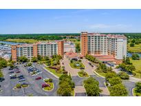 Stunning aerial view of a resort featuring multiple buildings, lush landscaping, parking, and a nearby golf course at 8121 Amalfi Pl. # 4706, Myrtle Beach, SC 29572