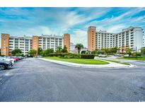 Beautiful exterior view of condo complex featuring a circular drive, lush landscaping, and ample parking at 8121 Amalfi Pl. # 7-805, Myrtle Beach, SC 29572
