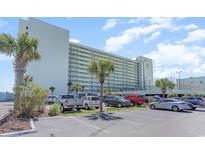 Multi-story condominium building with ample parking and a view of palm trees on a sunny day at 9400 Shore Dr. # 124, Myrtle Beach, SC 29572