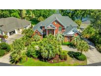 Stunning brick home with lush landscaping, a circular driveway, and mature palm trees at 1119 Links Rd., Myrtle Beach, SC 29575