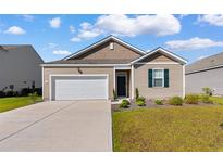 Charming single-story home featuring a manicured lawn, attached garage, and neutral siding with dark shutters at 1704 Perthshire Loop, Myrtle Beach, SC 29579