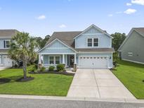 Charming two-story home with a manicured lawn, a two-car garage, and a welcoming front porch at 223 Southgate Ct., Pawleys Island, SC 29585