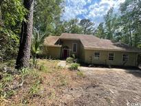 Home with red door, siding, surrounded by lush green trees in a well-lit outdoor setting at 2862 Loblolly Ave., Little River, SC 29566