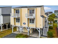 Inviting yellow exterior featuring double balconies, elevated design, and stylish staircase entry at 39 Newport St., Ocean Isle Beach, NC 28469