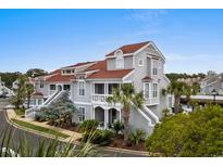 Coastal home featuring multiple decks and stairs, a gray facade, and red roof, set among lush palm trees at 4396 Baldwin Ave. # 30, Little River, SC 29566