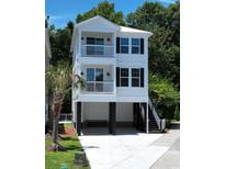 Two-story stilt home featuring balconies, dark shutters, and a concrete driveway and stairs at 52 Fish Shack Alley, Murrells Inlet, SC 29576