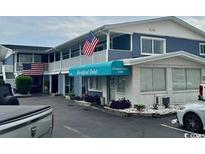 Charming multi-unit building featuring a blue awning with the property name and American flags displayed at 5409 N Ocean Blvd. # 111, North Myrtle Beach, SC 29582