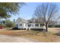 Charming two-story home with a covered front porch, manicured lawn, and mature trees at 589 Loop Circle, Longs, SC 29568