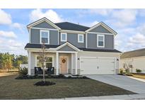 Charming two-story home featuring a two-car garage and a welcoming front porch with stylish seating at 7094 Watercress St, Myrtle Beach, SC 29579