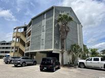 Three story condo building with weathered gray siding and ground level parking at 1101 Possum Trot Rd. # A202, North Myrtle Beach, SC 29582