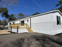 A bright white mobile home features a wooden deck and black iron fence at 2705 Capricorn Dr., Myrtle Beach, SC 29575