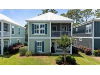 Charming two-story home featuring a screened porch and a light green exterior with blue shutters at 281 Lumbee Circle, Pawleys Island, SC 29585