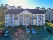 Three-story building with yellow siding, white trim, and multiple staircases, surrounded by parking and trees at 5822 Longwood Dr. # 104, Murrells Inlet, SC 29576