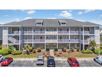 Three-story condo building featuring private balconies, well-manicured landscaping, and ample parking in front at 600 Heathrow Dr. # 1084, Myrtle Beach, SC 29579