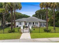 Charming single-story home featuring a secure black fence, lush lawn, and walkway leading to the front door at 6401 N Ocean Blvd., Myrtle Beach, SC 29572