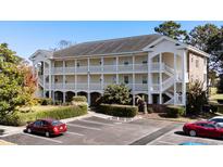 Beautiful two-story condo building with white siding, balconies, manicured landscaping, and ample parking at 703 Riverwalk Dr. # 303, Myrtle Beach, SC 29579
