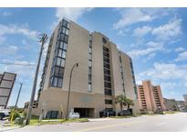 Exterior view of condo building with beige walls and blue signage against a partly cloudy sky at 1425 S Ocean Blvd. # 2A, North Myrtle Beach, SC 29582