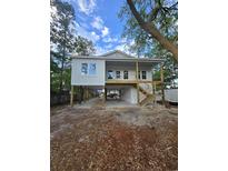 Two-story stilt home featuring white siding, exposed wooden beams and a staircase leading to a second-story porch at 2414 Gann Ave., North Myrtle Beach, SC 29582