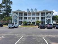 Three-story building featuring private balconies, white columns, and a parking lot at 330 S Middleton Dr. # 603, Calabash, NC 28467