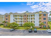 Beautiful multi-story condo building with yellow and brick accents and lush landscaping at 4890 Luster Leaf Circle # 201, Myrtle Beach, SC 29577