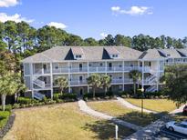 Three-story condo building with stairs, palm trees, a green lawn, and ample parking at 6253 Catalina Dr. # 534, North Myrtle Beach, SC 29582