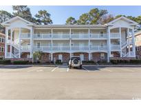 Three-story condo building with exterior stairs, white railings, and ample parking in a landscaped community at 690 Riverwalk Dr. # 201, Myrtle Beach, SC 29579