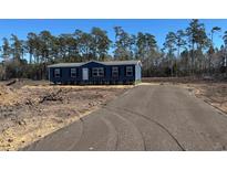 Charming blue home with black shutters and a welcoming front porch nestled amongst the trees at 1315 Rabbit Ln., Conway, SC 29526