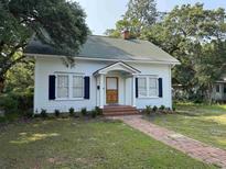Charming white house with blue shutters, a brick pathway, and mature trees in a tranquil setting at 1403 9Th Ave., Conway, SC 29526