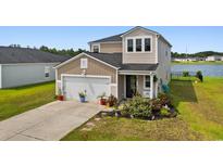 Charming two-story home featuring attached garage, landscaped yard, and lake view at 196 Cypress Tree Loop, Longs, SC 29568
