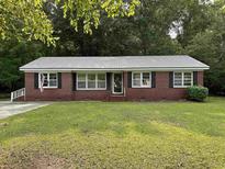 Charming brick home with a well-manicured lawn, gray metal roof, and black shutters at 205 S Oliver Blvd., Hemingway, SC 29554