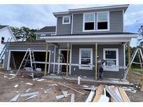 Two-story home featuring gray siding, white trim, a front porch, and an attached garage ready for final construction at 3038 Palma Way, Myrtle Beach, SC 29579