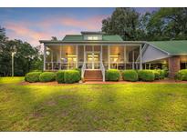 Inviting home featuring a spacious screened porch, beautiful landscaping, and warm lighting at dusk at 3231 Center Rd., Georgetown, SC 29440
