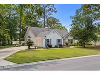 Charming single-story home with white siding, blue shutters, manicured lawn, mature trees, and a paved driveway at 4314 Turtle Ln., Little River, SC 29566