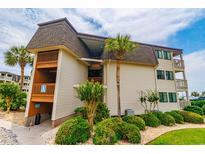 Charming condo building featuring lush landscaping, tan siding, a brown roof, and private wooden balconies at 5601 N Ocean Blvd. # A-307, Myrtle Beach, SC 29577