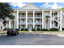 Three-story condo building with white columns, ample parking, and neatly landscaped grounds at 6010 Windsor Green Way # 301, Myrtle Beach, SC 29579
