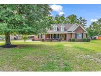 Charming brick home with a lush front yard, mature trees, and a welcoming front porch at 6161 Inman Circle, Conway, SC 29526