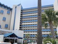 Ocean Reef Resort exterior view featuring blue and white facade, palm trees, and blue awning at 7100 N Ocean Blvd. # 316, Myrtle Beach, SC 29572
