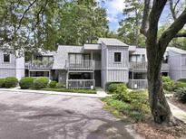 Inviting exterior featuring a townhouse with grey siding and a wooden railed porch surrounded by lush landscaping at 88 Salt Marsh Circle # 22F, Pawleys Island, SC 29585