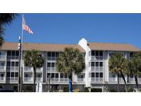 Low-rise condo building with a three-story exterior and a well-maintained facade surrounded by palm trees and the American flag at 9571 Shore Dr. # 318, Myrtle Beach, SC 29572
